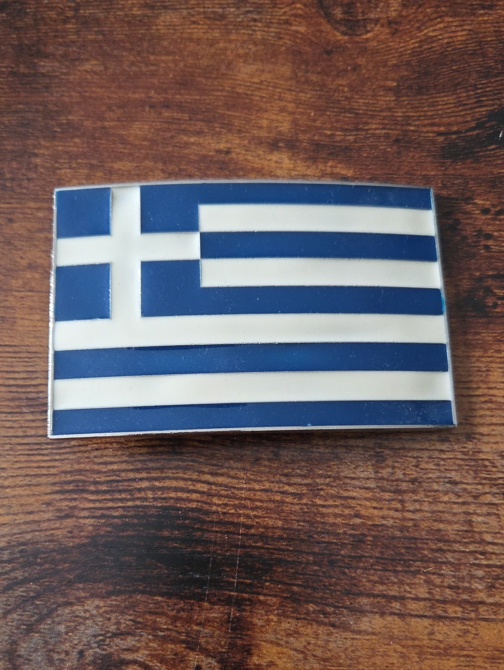 metal belt buckle featuring the blue and white flag of Greece.